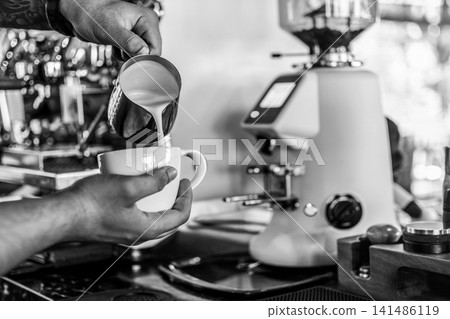 Barista making a Cappuccino coffee in modern coffeeshop with professional equipment  BW Black and White stock photo 141486119