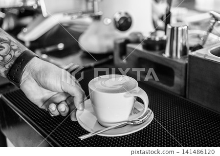 Barista making a Cappuccino coffee in modern coffeeshop with professional equipment  BW Black and White stock photo 141486120