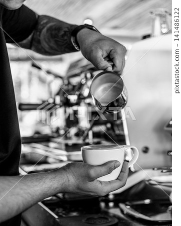 Barista making a Cappuccino coffee in modern coffeeshop with professional equipment  BW Black and White stock photo 141486122