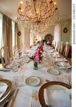 Elegant Luxury Dining Table With Crystal Chandelier and Floral Centerpieces for Banquet Reception Elegant Luxury Dining Table With Crystal Chandelier and Floral Centerpieces for Banquet Reception 141486157