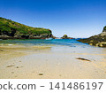 Sunny Sandy Beach Cove With Boats, Rocky Cliffs and Clear Blue Sea on a Summer Day 141486197