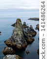 Rugged Sea Stacks and Rocky Coastline Under Overcast Sky With Calm Blue Ocean Horizon 141486264