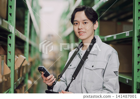 一名正在倉庫管理庫存的男子。 一名正在倉庫管理庫存的男子。 141487001