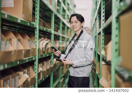 A man managing inventory in a warehouse A man managing inventory in a warehouse 141487002