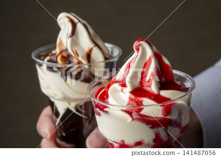 White soft-serve ice cream topped with red and brown sauce. White soft-serve ice cream topped with red and brown sauce. 141487056
