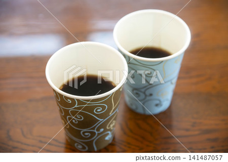 Coffee in decorative paper cups lined up on a wooden table Coffee in decorative paper cups lined up on a wooden table 141487057