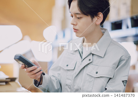 一名身穿工作服的男子正在清點庫存。 一名身穿工作服的男子正在清點庫存。 141487370