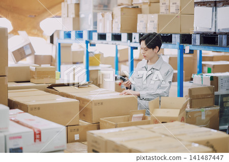 A man in work clothes managing inventory A man in work clothes managing inventory 141487447
