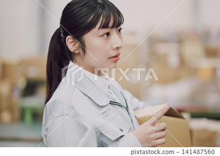 檢查貨物的婦女在倉庫裡 檢查貨物的婦女在倉庫裡 141487560