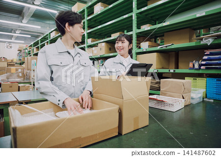 Young men and women working in a warehouse Young men and women working in a warehouse 141487602