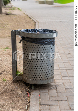 Trash can next to a pedestrian path in a square Trash can next to a pedestrian path in a square 141487778