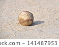 A baseball rolling on a dirt field 141487953