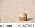 A baseball rolling on a dirt field 141487954