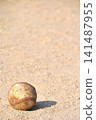 A baseball rolling on a dirt field 141487955