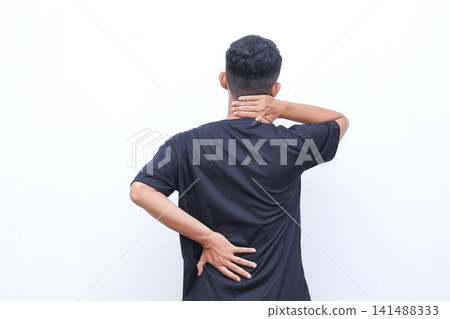 Man stands backlit, clutching neck and lower back. He appears strained, possibly suffering from discomfort or pain. Simple white background isolates the subject, drawing focus. Ideal for healthcare Man stands backlit, clutching neck and lower back. He appears strained, possibly suffering from discomfort or pain. Simple white background isolates the subject, drawing focus. Ideal for healthcare 141488333