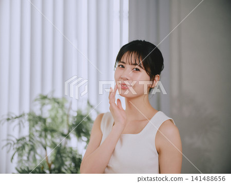一位年輕女子感到皮膚濕潤 一位年輕女子感到皮膚濕潤 141488656