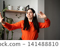 Smiling young woman wearing headphones gesturing in home office setting. Remote work communication and online presentation 141488810