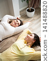 Two women relaxing in a cozy, bright bedroom with a journal and plant nearby. Cozy lifestyle and slow living with relaxation and self-reflection 141488820