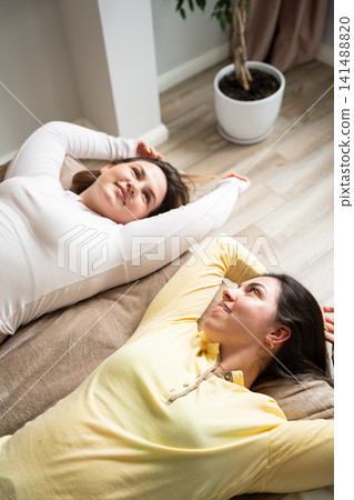 Two women relaxing in a cozy, bright bedroom with a journal and plant nearby. Cozy lifestyle and slow living with relaxation and self-reflection Two women relaxing in a cozy, bright bedroom with a journal and plant nearby. Cozy lifestyle and slow living with relaxation and self-reflection 141488820