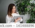Young woman using tablet for digital planning in a home office environment. Seamless workflow paperless office and small business management 141488896