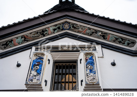A gable with a dragon plaster relief and lattice windows. A gable with a dragon plaster relief and lattice windows. 141489028