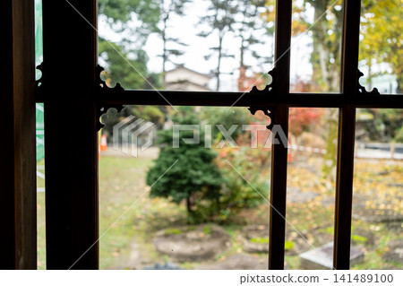 Autumn foliage garden viewed through decorative metal fittings 141489100