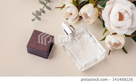 Perfume bottle with wooden cap with blooming floral decorations on a pastel beige background 141489226