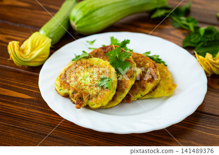 Healthy zucchini pancakes with parsley garnish on white plate Healthy zucchini pancakes with parsley garnish on white plate 141489376
