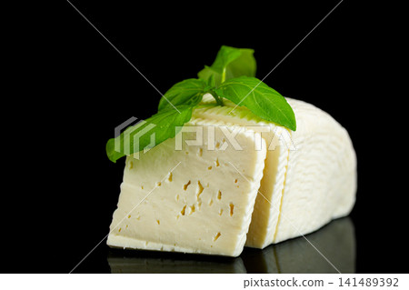Natural homemade white cheese with basil garnish on reflective black surface Natural homemade white cheese with basil garnish on reflective black surface 141489392
