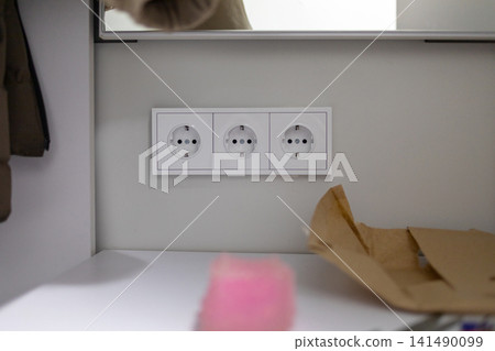 Electrical circuit breakers mounted beside braided water hoses and red shutoff valves on a green wall in a utility room, showing residential electrical and plumbing equipment indoors 141490099
