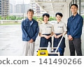Four cleaning staff members, two men and one woman, lined up in front of the cleaning cart. 141490266
