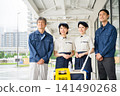 Four cleaning staff members, two men and one woman, lined up in front of the cleaning cart. 141490268