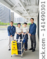 Four cleaning staff members, two men and one woman, lined up in front of the cleaning cart. 141490301