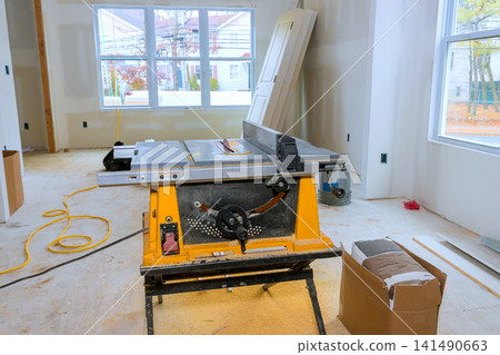 Woodworking table saw is placed in room undergoing renovation. Woodworking table saw is placed in room undergoing renovation. 141490663