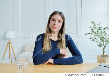 Concerned young woman looking directly at camera gesturing frustration during video call 141490666
