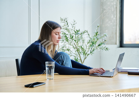 Young woman university student sitting at desk with laptop, typing writing studying Young woman university student sitting at desk with laptop, typing writing studying 141490667