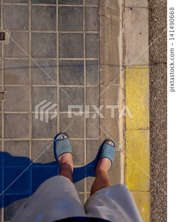 Casual person standing on a tiled city sidewalk 141490668