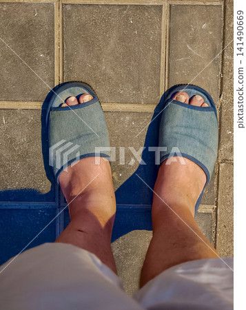 Person walking outside in blue slippers on pavement Person walking outside in blue slippers on pavement 141490669