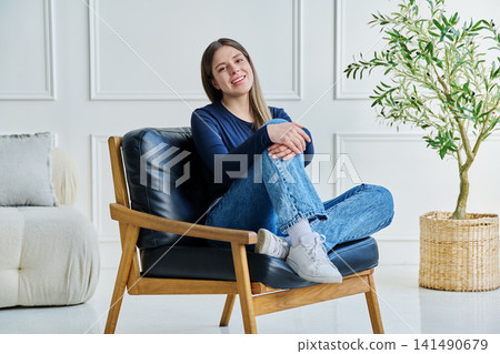 Portrait of relaxed beautiful young woman sitting at home on chair Portrait of relaxed beautiful young woman sitting at home on chair 141490679