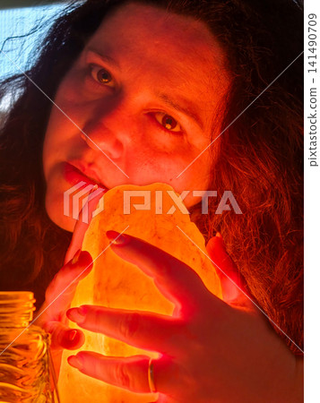 Woman holding glowing salt lamp for warmth Woman holding glowing salt lamp for warmth 141490709