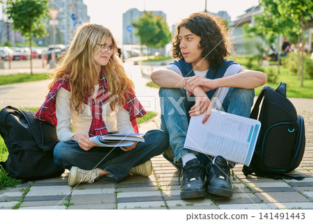 Two teenage students talking outdoors while studying together in city park Two teenage students talking outdoors while studying together in city park 141491443