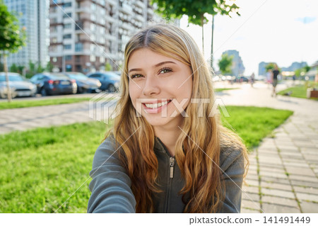 Young attractive woman taking a selfie outdoors in modern city street on sunny summer day Young attractive woman taking a selfie outdoors in modern city street on sunny summer day 141491449