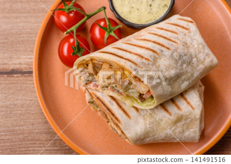 Grilled chicken shawarma or doner with tomatoes, cucumber, and sauces, takeout food Grilled chicken shawarma or doner with tomatoes, cucumber, and sauces, takeout food 141491516