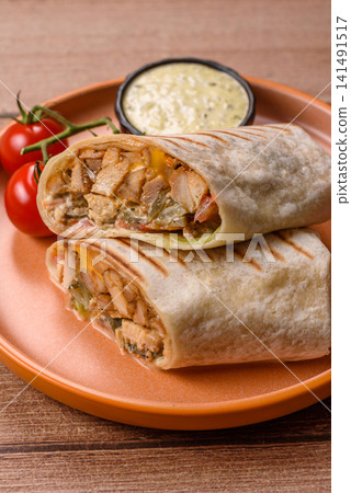 Grilled chicken shawarma or doner with tomatoes, cucumber, and sauces, takeout food Grilled chicken shawarma or doner with tomatoes, cucumber, and sauces, takeout food 141491517