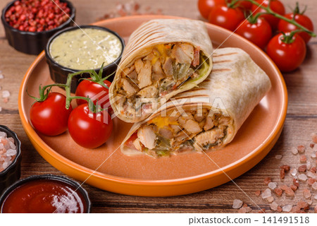 Grilled chicken shawarma or doner with tomatoes, cucumber, and sauces, takeout food Grilled chicken shawarma or doner with tomatoes, cucumber, and sauces, takeout food 141491518