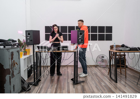 DJ student learning track mixing techniques in studio with hands-on equipment guidance. DJ, student, track mixing, equipment, learning 141491829