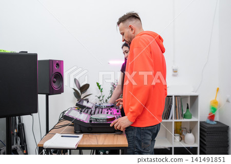 DJ student learning track mixing techniques in studio with hands-on equipment guidance. DJ, student, track mixing, equipment, learning DJ student learning track mixing techniques in studio with hands-on equipment guidance. DJ, student, track mixing, equipment, learning 141491851