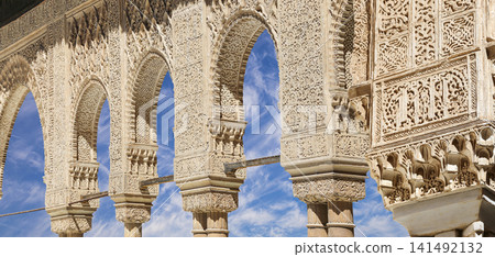 Arches in Islamic (Moorish) style (against the background of a beautiful sky with clouds) in Alhambra, Granada, Spain Arches in Islamic (Moorish) style (against the background of a beautiful sky with clouds) in Alhambra, Granada, Spain 141492132