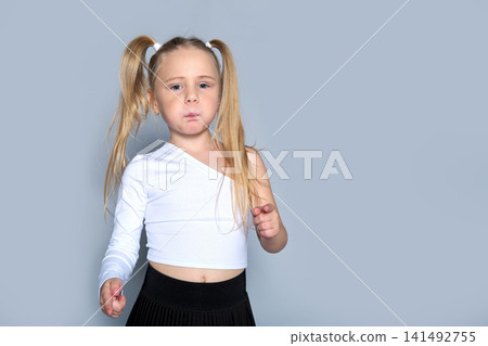 Focused child in dance attire, with her hair tied in playful pigtails, capturing a moment of determination and poise. Focused child in dance attire, with her hair tied in playful pigtails, capturing a moment of determination and poise. 141492755