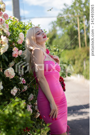 Adult blonde woman leans back with closed eyes beside blooming roses in warm sunlight. Suitable for relaxation, grace, summer fashion, and floral lifestyle content. Adult blonde woman leans back with closed eyes beside blooming roses in warm sunlight. Suitable for relaxation, grace, summer fashion, and floral lifestyle content. 141493065